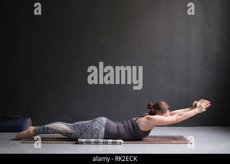Woman practicing yoga, stretching in Salabhasana exercise, Double Leg Kicks pose Stock Photo
