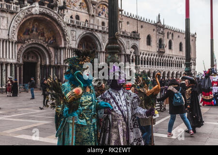 VENICE, ITALY - FEBRUARY 09 2018: Pair of colorful Venetian masks dressed in San Marco Square Stock Photo