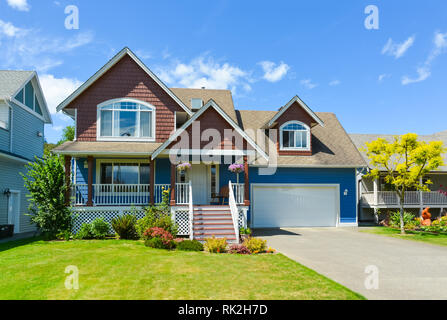 Blue residential house with concrete driveway in front and blue sky background. Stock Photo