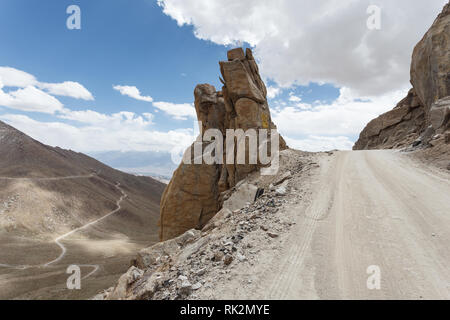 Biking the narrow dirt road ahead winding over the barren mountains of the Khardungla Pass in Tibet Stock Photo
