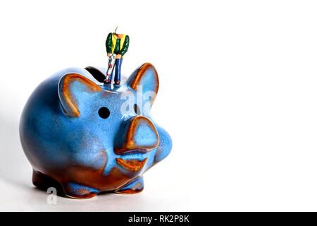 Conceptual diorama image of miniature figure with a road drill trying to open a piggy bank