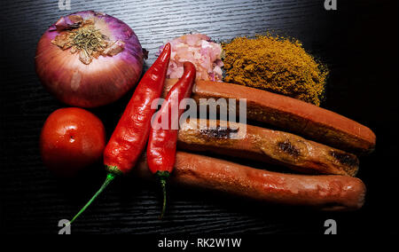 Popular Nigerian Meals - Grilled Sausage Suya garnished with red pepper, tomatoes, onions and suya powder Stock Photo