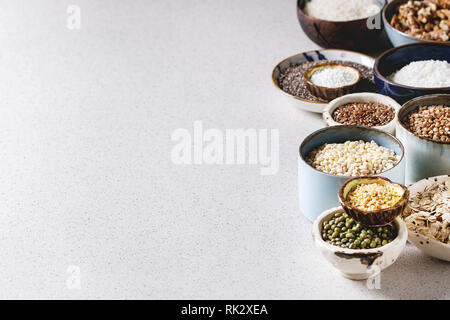 Variety of raw uncooked grains superfood cereal chia seeds, linen, sesame, mung bean, walnuts, tapioca, wheat, buckwheat, oatmeal, coconut, rice in ce Stock Photo