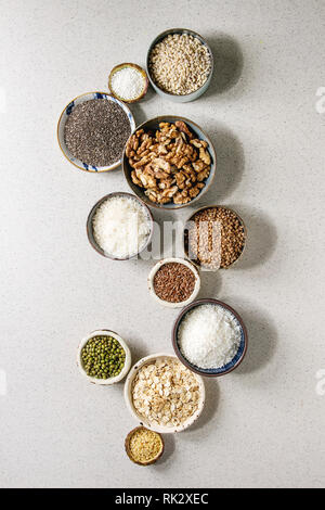Variety of raw uncooked grains superfood cereal chia, linen, sesame, mung bean, walnuts, tapioca, wheat, buckwheat, oatmeal, coconut, rice in ceramic Stock Photo