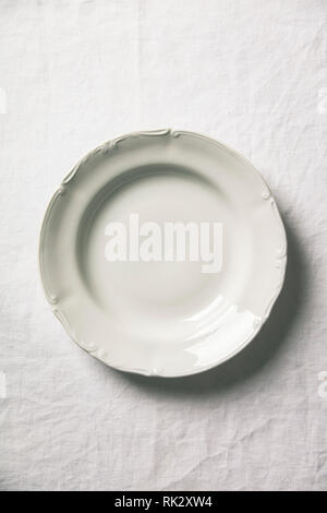 Empty soup plate on white linen tablecloth Stock Photo