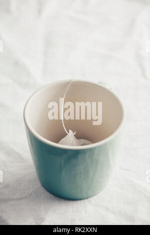 Green ceramic mug with teabag on white napkin Stock Photo