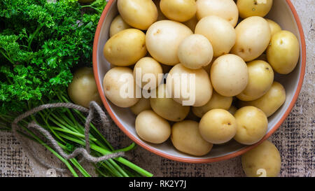 Whole washed potatoes in a bowl with a bunch of parsley. Stock Photo