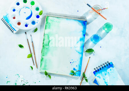 Drawing spring concept with artist tools, green and blue watercolor sketchbooks, brushes and color palette on a light background with copy space Stock Photo