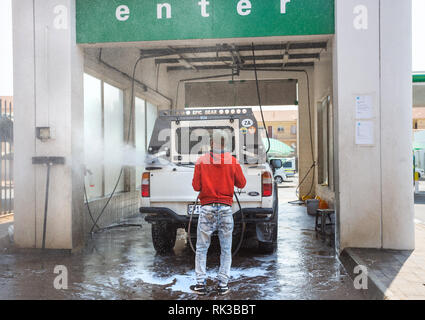 Pretoria, South Africa, 22 August - 2018: Car wash with attendant washing car with spray. Stock Photo
