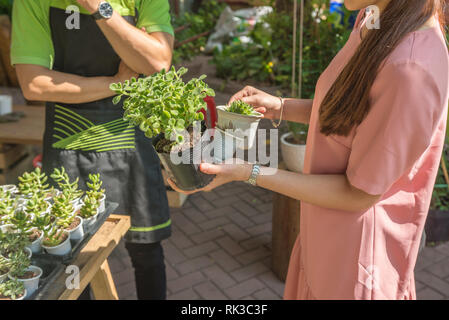 Female customer asking staff for plant advice at garden center Stock Photo