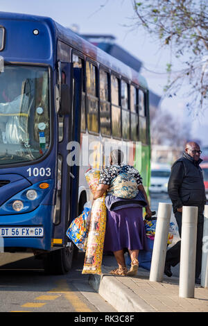 Johannesburg, South Africa, 24 August - 2018: Passenger getting on public bus with luggage in her arms. Stock Photo