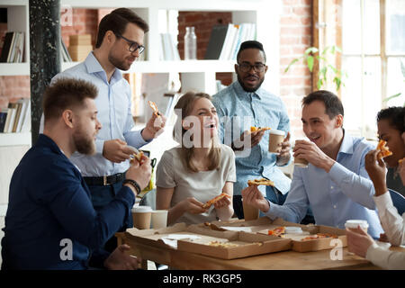 Happy diverse team people talking laughing eating pizza in office Stock Photo