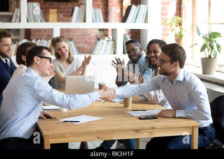 Happy partners shake hands get team applause after successful negotiations Stock Photo