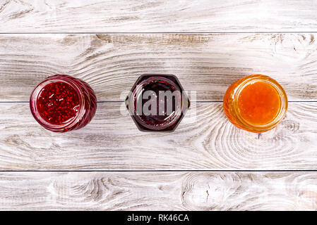 Three bowls with different jams on wooden table. Top view. Stock Photo