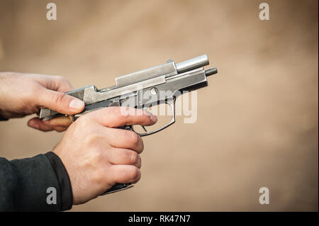 Detail view of shooter rack a pistol slide. Racking the slide of handgun. Pulling back and reloading gun. Side view Stock Photo