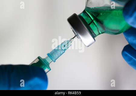 Physician injector arms in sterile uniform holding syringe Stock Photo