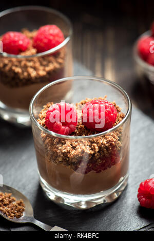 Chocolate dessert in glasses with raspberries. Chocolate mousse or pudding in portion glasses with fresh berries, copy space. Stock Photo