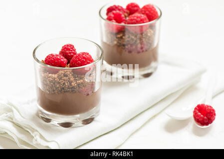 Chocolate dessert in glasses with raspberries. Chocolate mousse or pudding in portion glasses with fresh berries, copy space. Stock Photo