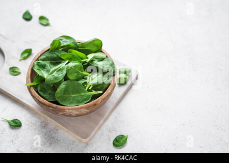 Baby spinach leaves in bowl on white background, copy space. Clean eating, detox, diet food ingredient - green organic spinach. Stock Photo