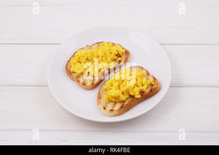 Scrambled eggs on two pieces of toast Stock Photo