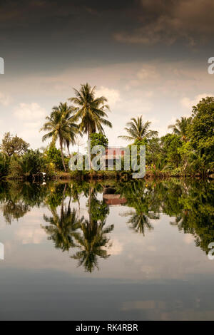 Cambodia, Koh Kong Province, Andoung Tuek, coconut palm trees shading house on banks of Preak Piphot River Stock Photo