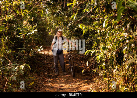 Cambodia, Koh Kong Province, Chi Phat village, senior female visitor walking with bicycle on village footpath Stock Photo