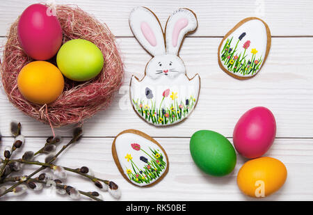 Gingerbread Easter set painted eggs and willow twig on white wooden background.  Easter Bunny and eggs, gingerbread Stock Photo