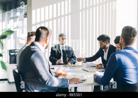 Indian business adviser analyzing company financial report shows documents with charts to Senior grey-haired investor discussing balance sheet data du Stock Photo