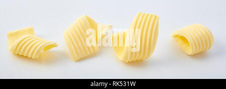 Set of different butter curls or rolls in a row in close-up on white surface background Stock Photo