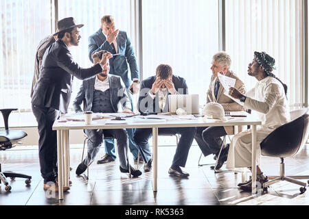 mixed race business people quarreling at desk in office. emotional conversation among foreign partners Stock Photo