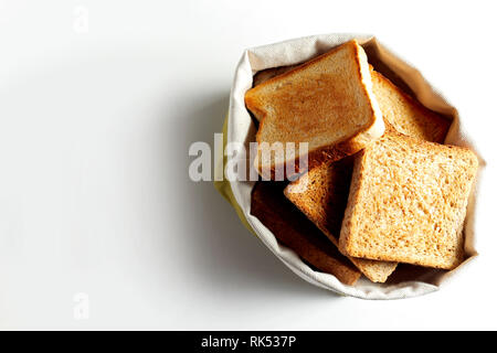 Fried toast bread slices put in white bag, and viewed from above on white background with shadow. Copy space Stock Photo