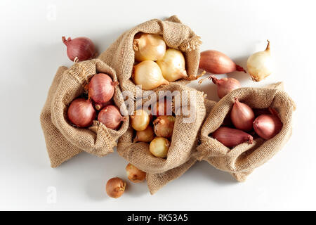 Burlap sack bags with various onions from local market, viewed from above and isolated on white background with shadow Stock Photo