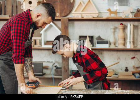 profession, carpentry, woodwork and family concept - carpentery masterclass for little children and their fathers to share basic knowledge of working  Stock Photo