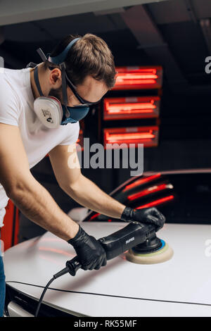 mechanic using an electric polishing device in the garage. close up side view photo. Stock Photo