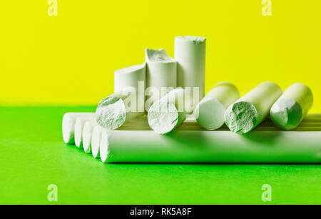Pieces of chalk on a green and yellow  background ,intact and broken pieces , studio shot Stock Photo