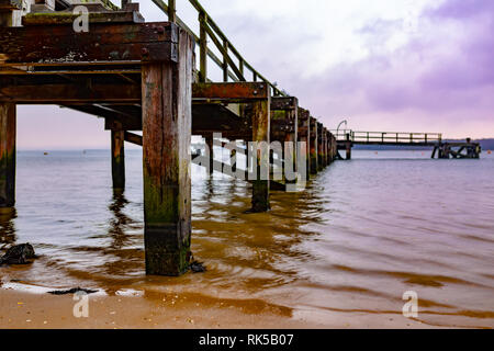 Landscape photograph taken beside Lake Drive Pier from shoreline under purple sky on an inner harbour beach, Poole, Dorset. Taken with wide open apert Stock Photo