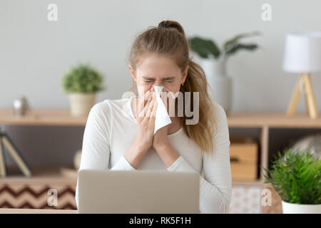 Ill young woman caught cold sneezing wiping running nose