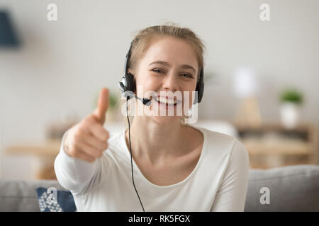 Satisfied happy girl wearing headset showing thumbs up giving recommendation Stock Photo