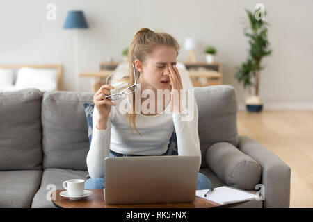 Fatigued woman feels eye strain rubbing eyes taking off glasses Stock Photo