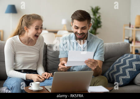 Excited couple screaming with joy reading good news in letter Stock Photo