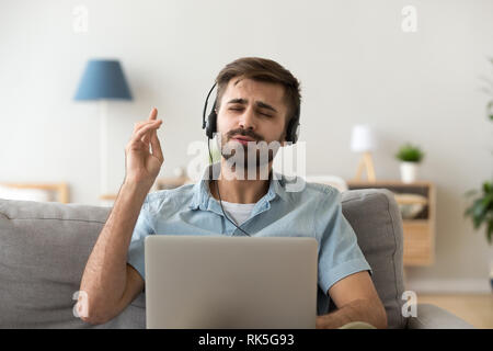 Melomane in headphones enjoying good music using online player application Stock Photo