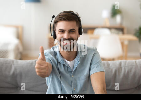 Happy young man wearing headset showing thumbs up giving recommendation Stock Photo
