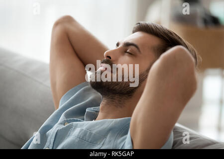 Relaxed happy young man resting having nap on comfortable couch Stock Photo