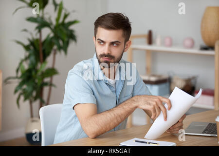 Serious thoughtful man holding papers thinking of problem solution Stock Photo