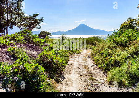 Dirt road leads to Lake Atitlan with San Pedro volcano in background,  Guatemalan highlands, Central America Stock Photo
