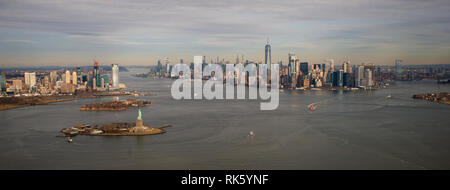 Manhattan Island viewed from a helicopter above New York Harbour bay looking north past Liberty island and the statue of liberty with Jersey City on t Stock Photo