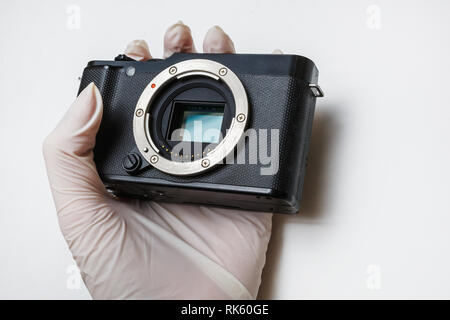 Close-up of mirrorless digital APS-C dirty camera matrix sensor cleaning and maintenance with swab, photographer cleaning photocamera on white backgro Stock Photo