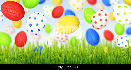 Cololrful Easter eggs falling at green grass on blue sky background Stock Photo