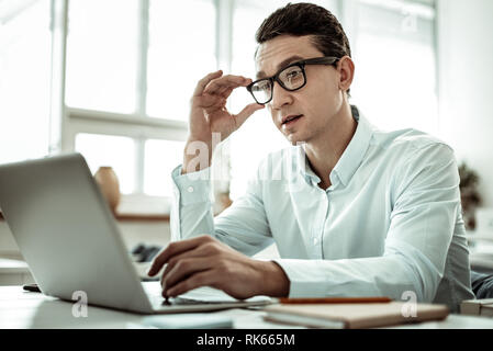 Attentive brunette man reading article in internet Stock Photo