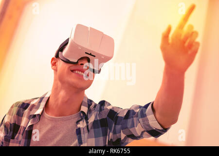Joyful glad guy experimenting in virtual reality Stock Photo